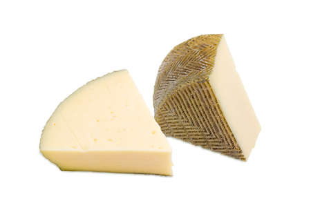 Two pieces of semi-hard Spanish cheese with dark coating manufactured from mixtures of cow and sheep milk on a light backgroundの写真素材