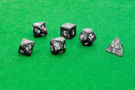 Set of specialized polyhedral dice with numbers used in role-playing games on a table with green clothの写真素材