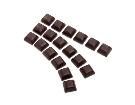 Square pieces of dark chocolate laid out in three rows on a light backgroundの写真素材