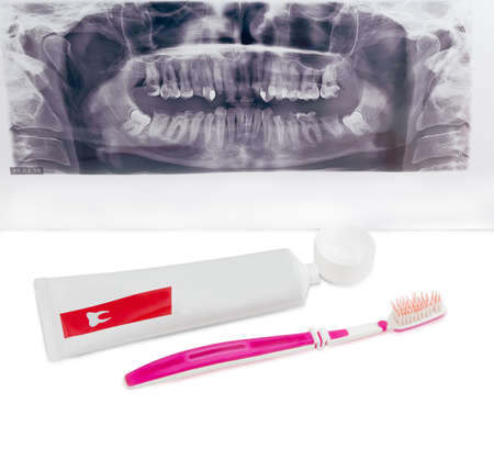 Toothbrush and open tube of toothpaste on background dental panoramic radiograph on a light backgroundの写真素材