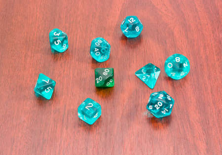 Set of blue and green specialized polyhedral dice with numbers used in role-playing games on a wooden surfaceの写真素材