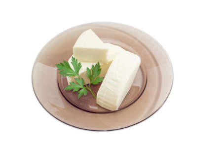 Three pieces of fresh mozzarella cheese and sprig of parsley on a dark glass dish on a light backgroundの写真素材