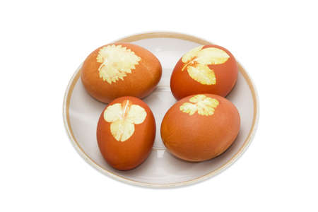 Several Easter eggs boiled with onion skins and leaf patterns on a saucer on a light backgroundの写真素材