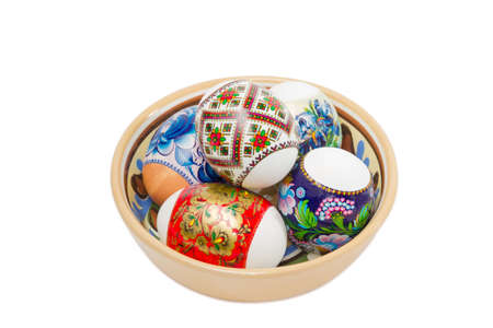 Several Easter eggs with a different patterns in a ceramic bowl on a light backgroundの写真素材