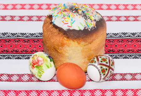 Easter cake decorated with white icing and colorful sugar decors and several Easter eggs with a...