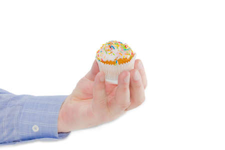Little Easter muffin decorated with white icing and colorful sugar decors in male hand on a light backgroundの写真素材