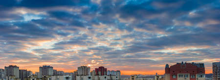 Panorama of a sunset over the housing estate with modern multi-storey apartment buildings in a big cityの写真素材