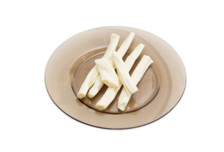 Several sticks of a brined chechil cheese on a dark glass dish on a light backgroundの写真素材