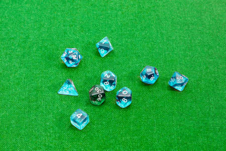 Set of blue and green specialized polyhedral dice with numbers used in role-playing games on a table with green clothの写真素材