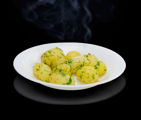 Boiled whole young potatoes of early ripening with butter, sprinkle with chopped dill on a white dish on a dark backgroundの写真素材