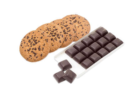 Several chocolate chip cookie and square pieces of dark chocolate in the opened packing on a light backgroundの写真素材