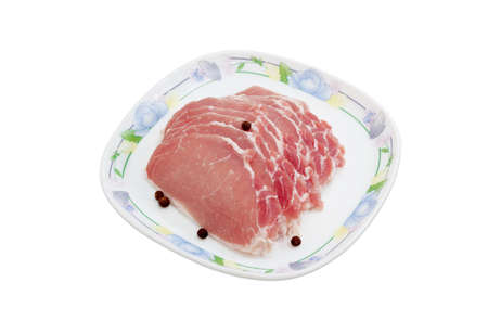 Sliced uncooked pork tenderloin and few peas allspiceon on a dish on a light backgroundの写真素材