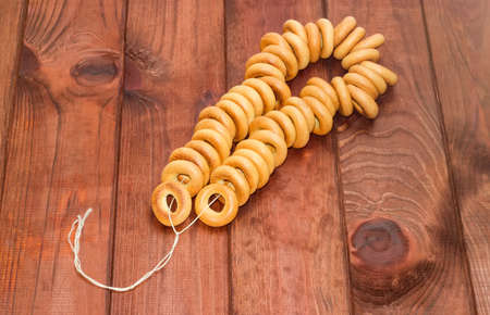 Bunch of small round bagels tied by cord on a dark wooden surfaceの写真素材