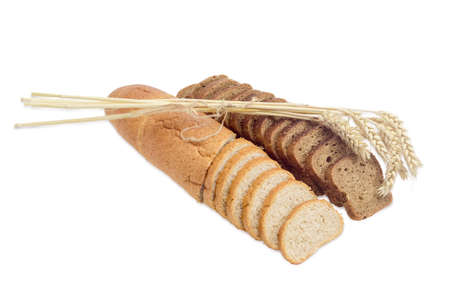 One partly sliced long loaf of wheat bread with bran, sliced brown bread with whole grain and bunch of wheat spikes on a light backgroundの写真素材