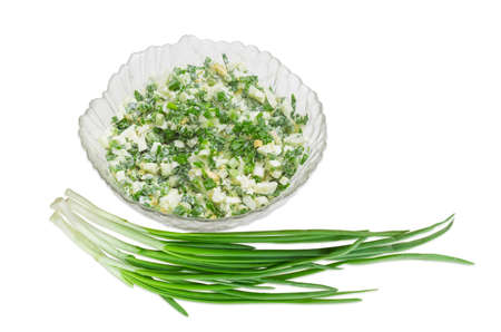 Spring salad with chopped green onions, boiled eggs and sour cream in a glass salad bowl and a bunch of green onions on a light backgroundの写真素材
