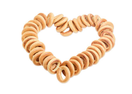 Bunch of small round bagels tied by cord and laid out in the form of heart on a light backgroundの写真素材