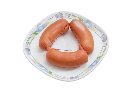 Bundle of three uncooked thick frankfurters on a dish on a light backgroundの写真素材