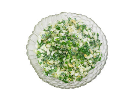Top view to a spring salad with chopped green onions, boiled eggs and sour cream in a glass salad bowl on a light backgroundの写真素材