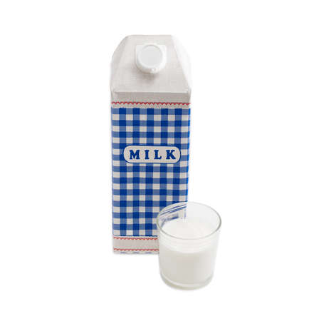 Plastic coated paper carton with pasteurized cows milk and a glass of milk on a light backgroundの写真素材