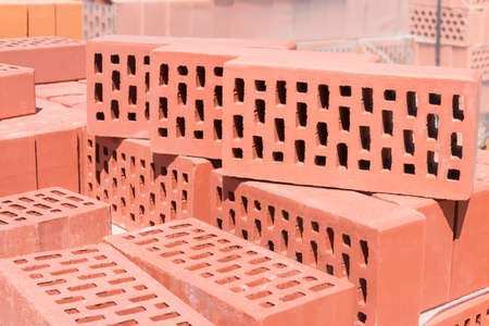 Several red perforated bricks with rectangular holes on another bricks closeup on the background of the other bricksの写真素材
