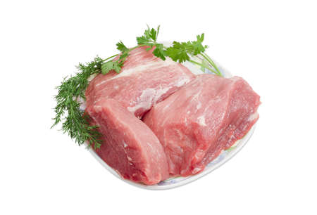 Several pieces of a fresh uncooked pork and sprigs of dill and parsley on plate on a light backgroundの写真素材
