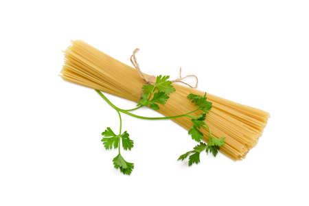 Bundles of uncooked dried long pasta and sprig of parsley on a light backgroundの写真素材