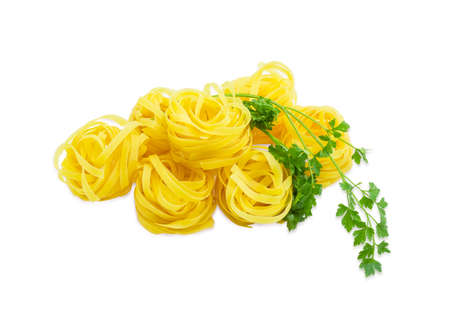Uncooked dried egg pasta tagliatelle and sprig of parsley on a light backgroundの写真素材