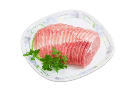 Sliced uncooked pork tenderloin and sprigs of parsley on dish on a light backgroundの写真素材