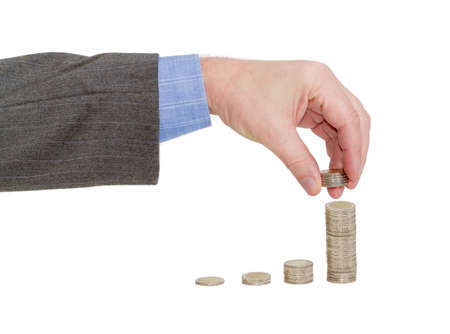 Male hand adds a several coins to the last column of the diagram consisting of columns of euro coins on a light backgroundの写真素材