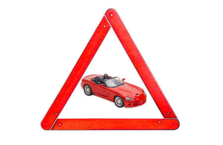 Red toy car cabriolet among warning triangle sign with red border on a light backgroundの写真素材