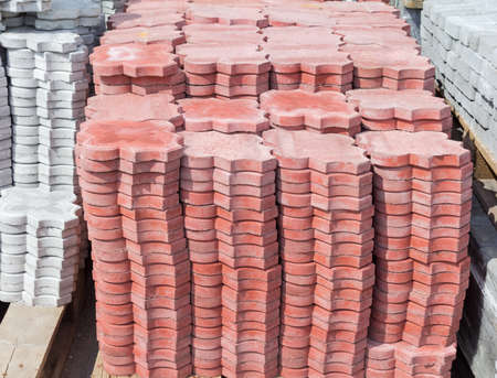 Red concrete pavement tiles with ornament made by vibration casting method stacked on a pallet on a warehouseの写真素材