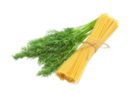 Bunch of uncooked dried long pasta and bundle of a fresh dill on a light backgroundの写真素材
