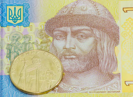 Coin one Ukrainian hryvnia with depicting of Kievan Rus Prince Volodymyr the Great against a background of fragment banknote one hryvniaの写真素材