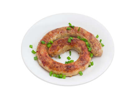 Fried homemade sausage sprinkled with chopped green onions on a white dishの写真素材