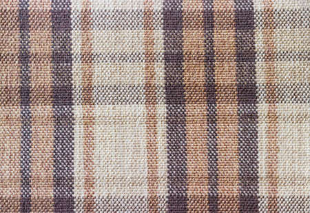 Background of coarse cloth with a large checkered pattern of black, brown and coffee colors closeup