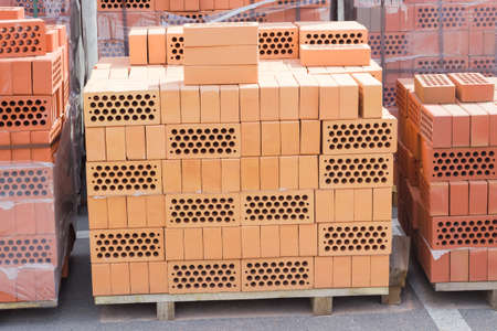 Wooden pallets of perforated yellow and red bricks with round holes on warehouseの写真素材