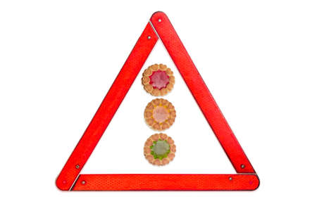 Biscuit with fruit jelly colors of traffic light , respectively, red, yellow and green, among warning triangle sign on a light backgroundの写真素材