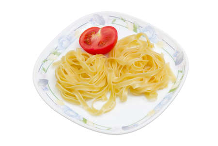 Boiled noodles tagliatelle and half fresh tomato on dish on a light backgroundの写真素材