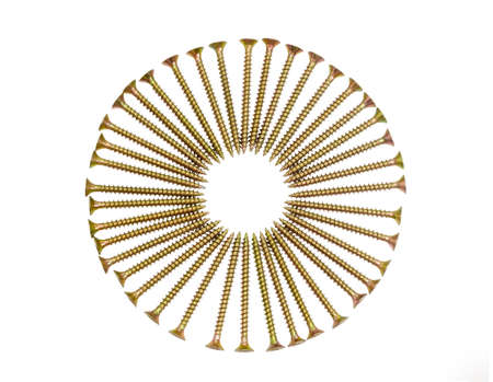Zinc plated chipboard screws with countersunk heads, stacked in a circle closeup on a light backgroundの写真素材