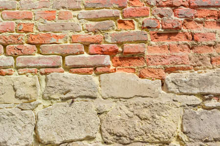 Background of a fragment of a medieval fortress wall, built of stone limestone and brickの写真素材