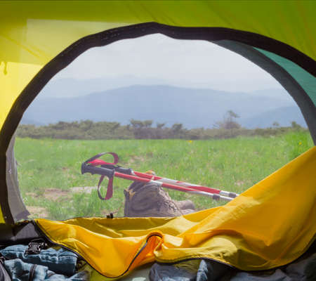 View to the mountains from the hiking tent through the open tent entrance and closed mosquito netの写真素材