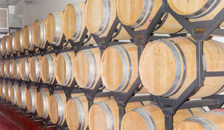 Steel shelving with rows of new oak barrels with wine on a warehouse in winery