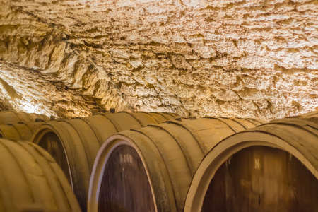 Fragment of underground wine cellar with old oak wine barrelsの写真素材