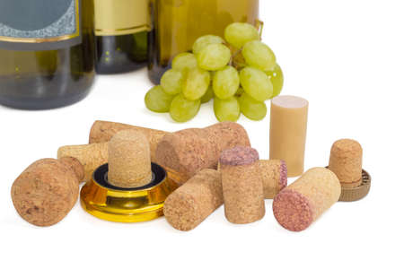 Several different traditional and synthetic wine corks on the background bottles of wine and cluster of white grapes closeup on a light backgroundの写真素材