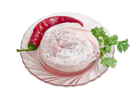 Frozen roll of pork belly covered by frost, chili pepper and twig of cilantro on a pink glass dish on a light backgroundの写真素材