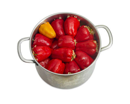 Cooked stuffed red and yellow bell peppers in a large stainless steel saucepan on a light backgroundの写真素材