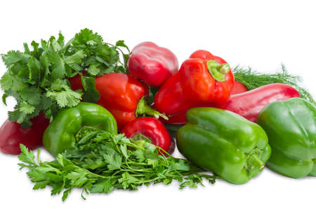 Several fresh green and red bell peppers among bundles of the parsley, cilantro, dill closeup on a light backgroundの写真素材