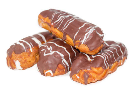 Several eclairs with whipped cream and chocolate icing closeup on a light backgroundの写真素材