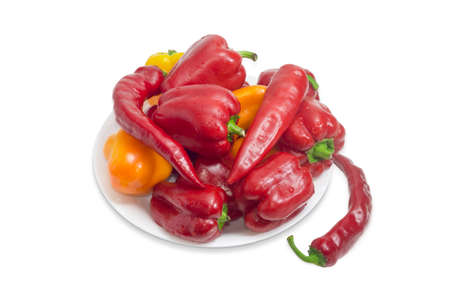 Washed red and yellow bell peppers and red peppers chili with water drops on white dish on a light backgroundの写真素材