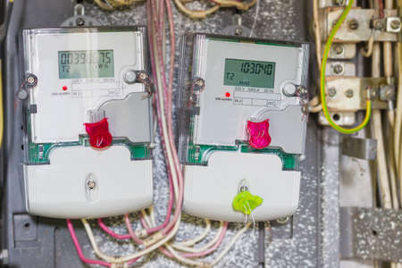 Two domestic digital solid-state electricity meter in transparent plastic case with variable-rate meters, mounted in distribution boardの写真素材